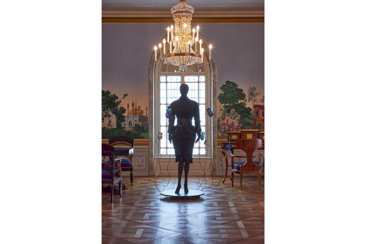 A Biedermeier-style room with a mannequin wearing a futuristic fashion design. 