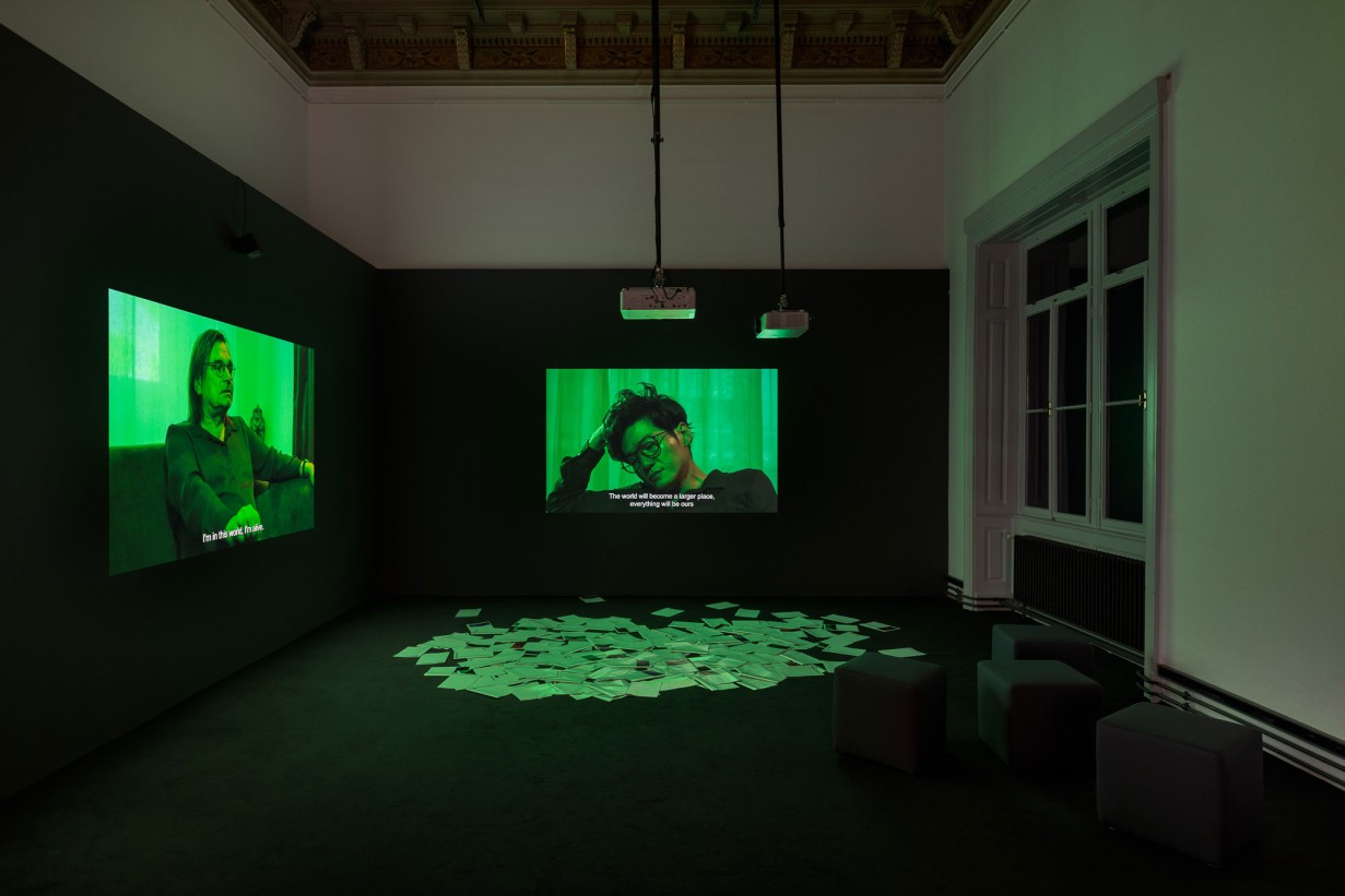 Dark room with one video projection each on the left and right wall.