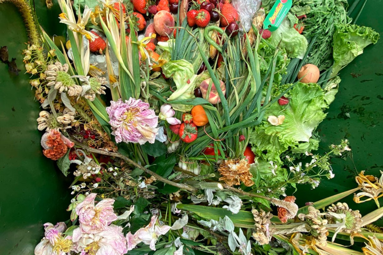 Gemüse, welke Blumen, Obst und Grünzeug sind zu einer Art Blumenstrauß arrangiert. 