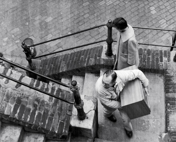 Person trägt Box über Stiegen nach oben, andere Person geht runter