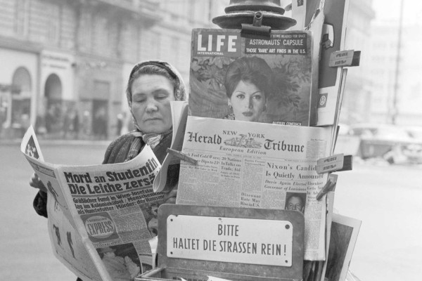 Black and white photograph of a woman at a newspaper stand