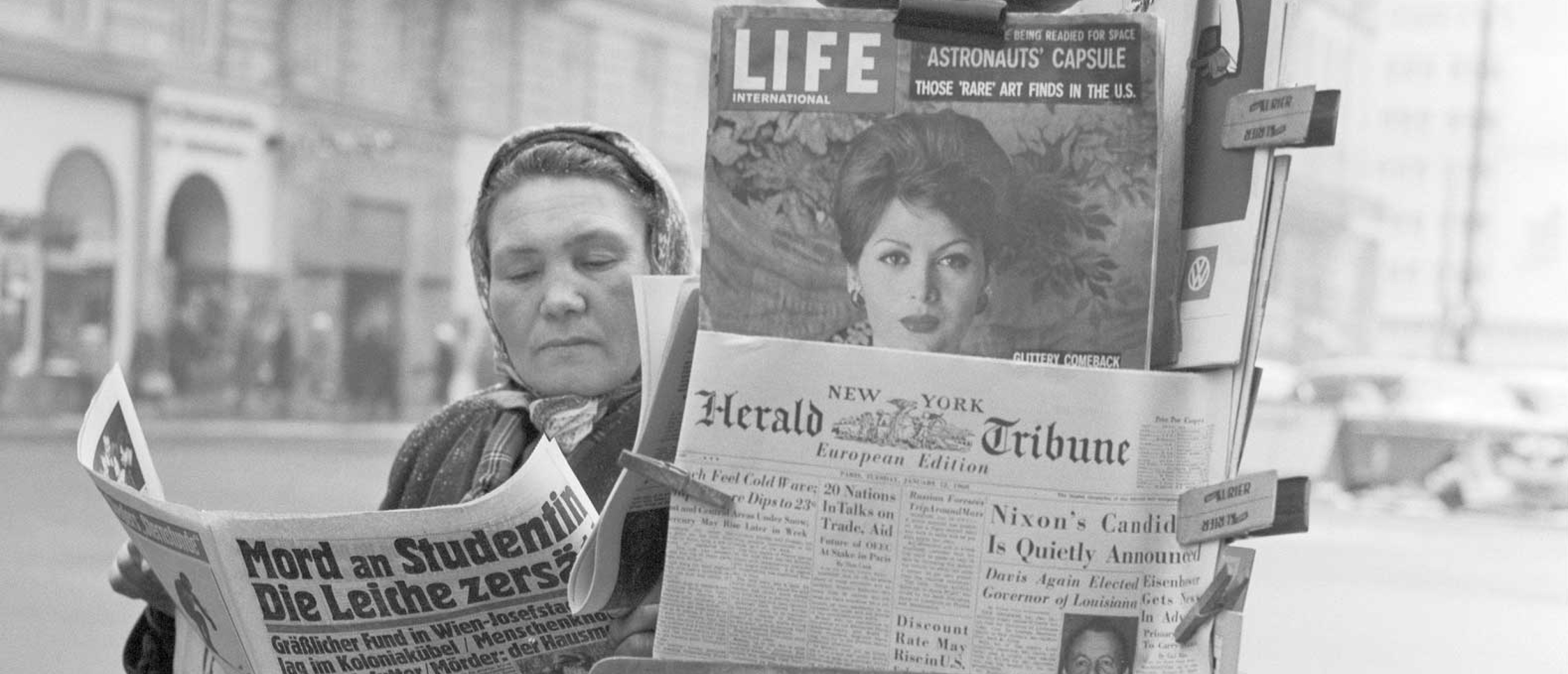 Schwarz weiß Fotografie von Frau an Zeitungsständer