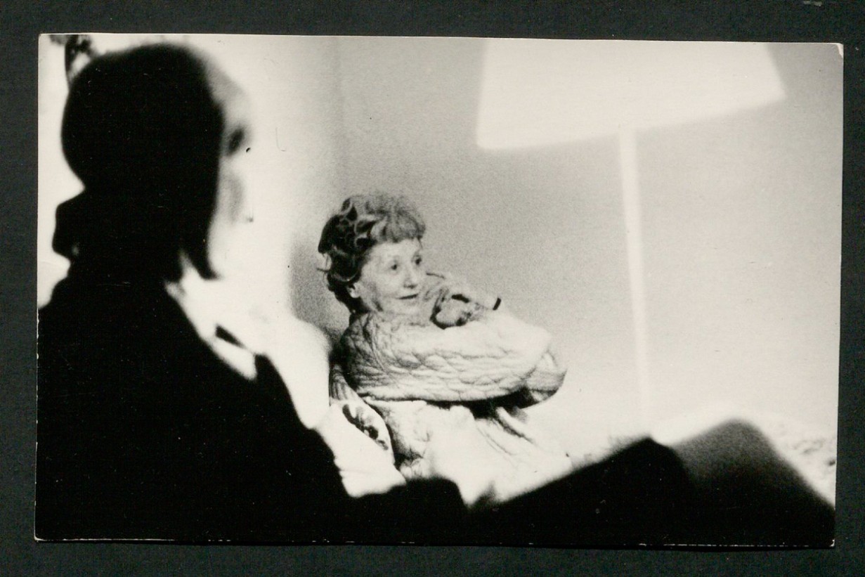 Schwarz-weiß Fotografie, zu sehen eine verschwommene Person im Vordergrund, eine Frau im Hintergrund