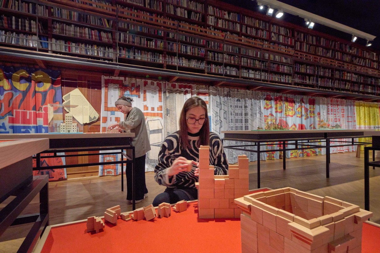 Ausstellungsansicht ARCHITEKTURBAUKÄSTEN 1890–1990. Die große Mitspielausstellung: Vitrinen und Besucher*innen