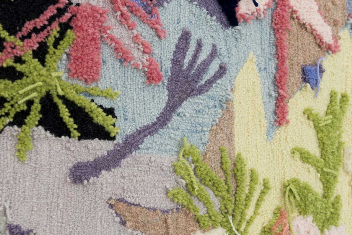 Detailausschnitt eines getuffteten Teppichs mit verschiedenen Farben.