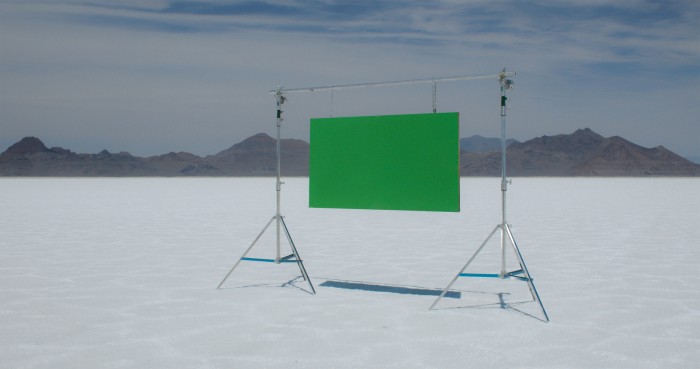 Ein grüner Bildschirm auf einem Ständer, der inmitten einer Wüstenlandschaft steht.