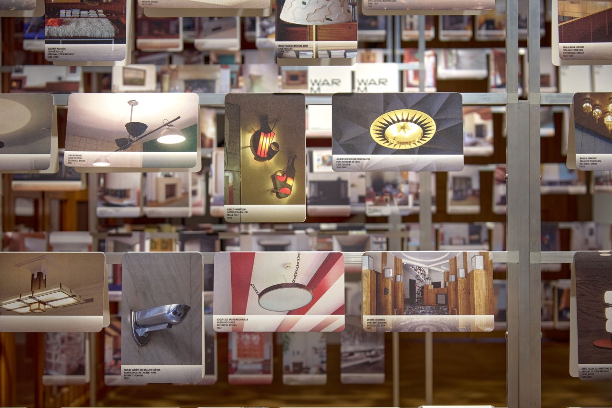 Many photos with detailed shots of architecture hang on scaffolding in an exhibition room.