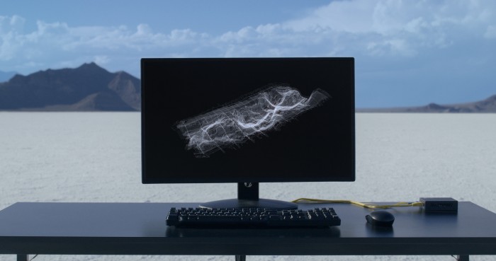 Ein Computerbildschirm auf einem Schreibtisch steht in einer Wüstenlandschaft. 