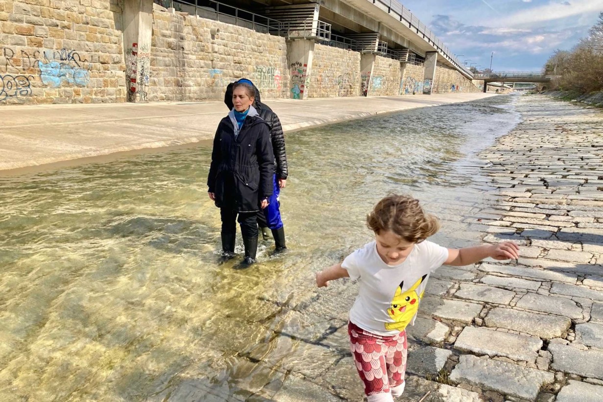 Ein Flussbett mit Steinen, zwei Personen: eine Frau, ein Kind