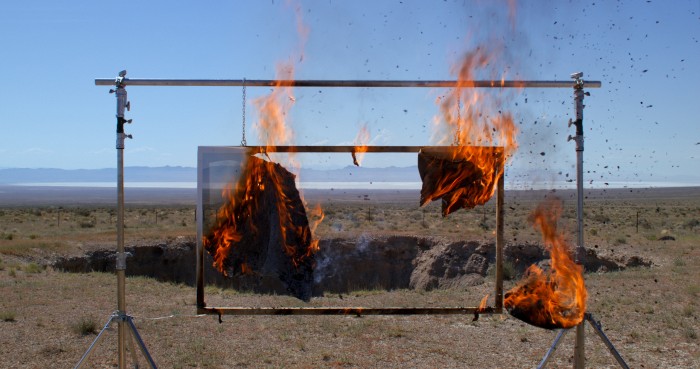 Eine Leinwand geht in einer Wüstenlandschaft in Flammen auf 