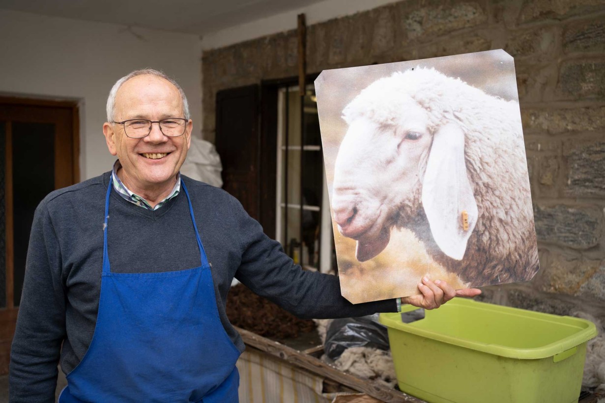 Ein weißer Mann hält ein Foto von einem Schaf in die Höhe