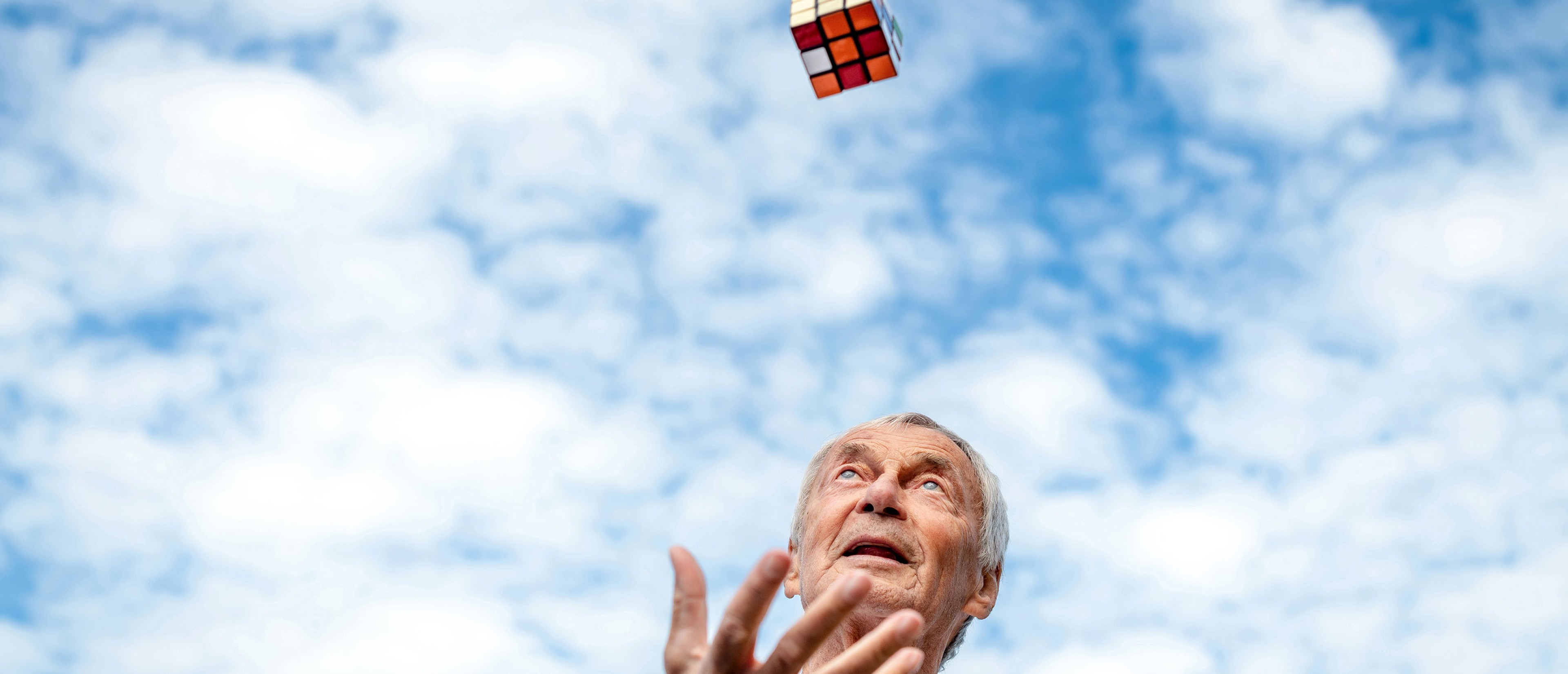 Ein Mann wirft einen Rubik Cube in die Luft