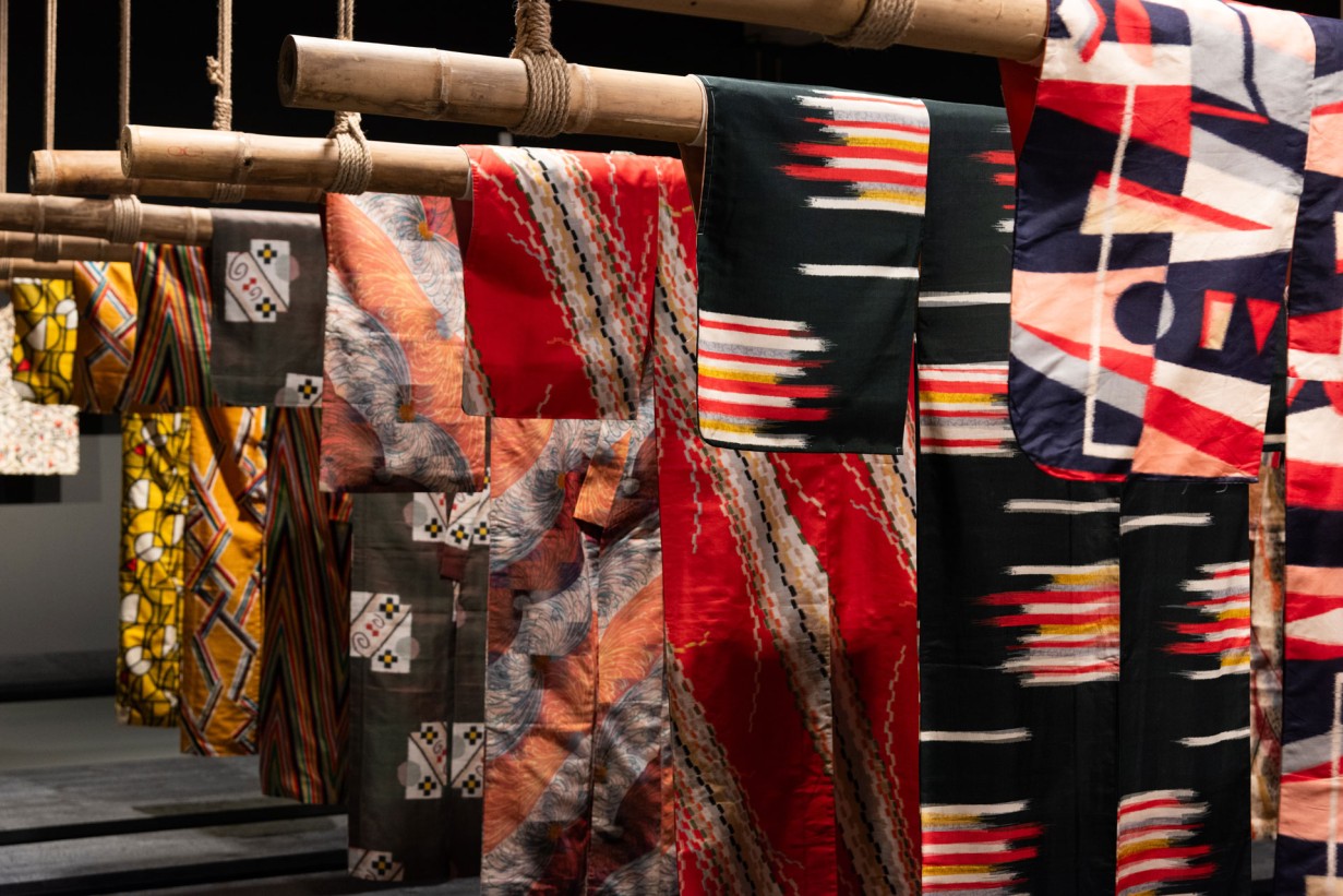 An exhibition room with colorful kimonos hanging from the ceiling