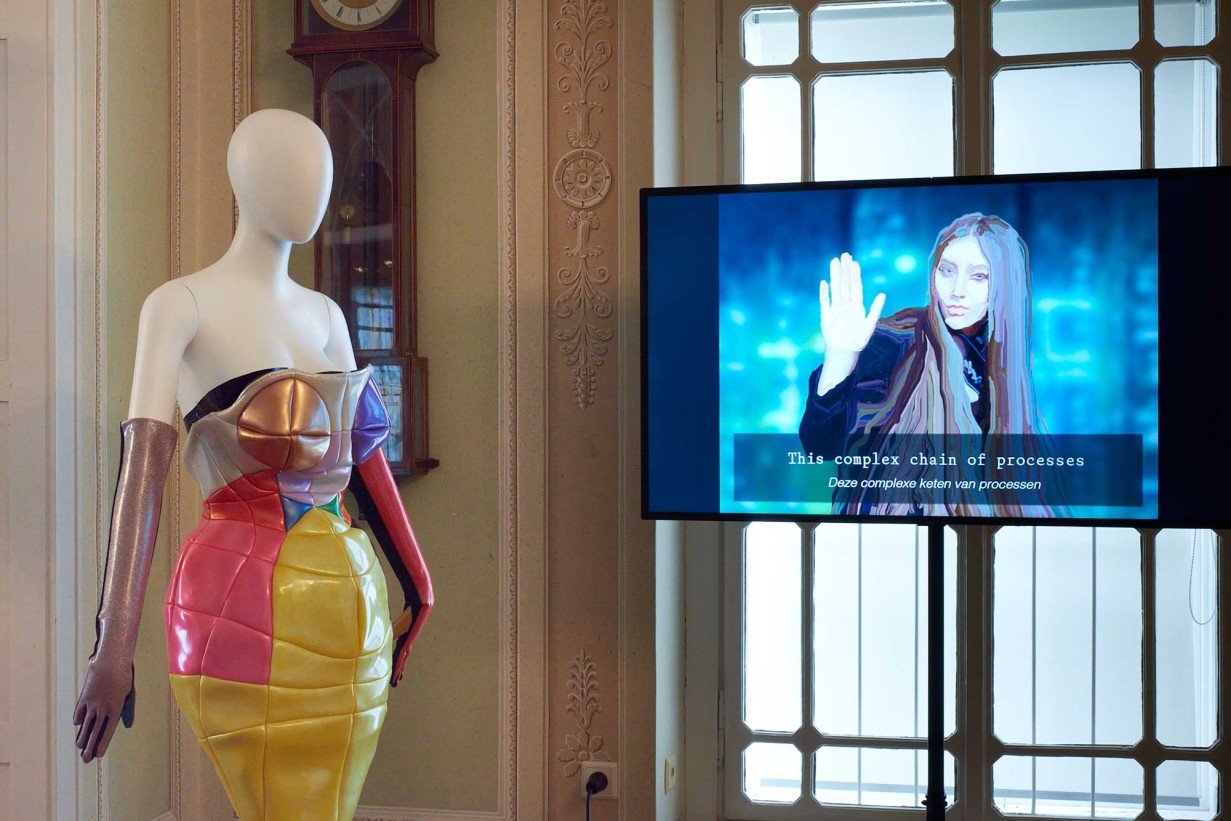 A mannequin with colorful dress and a screen.