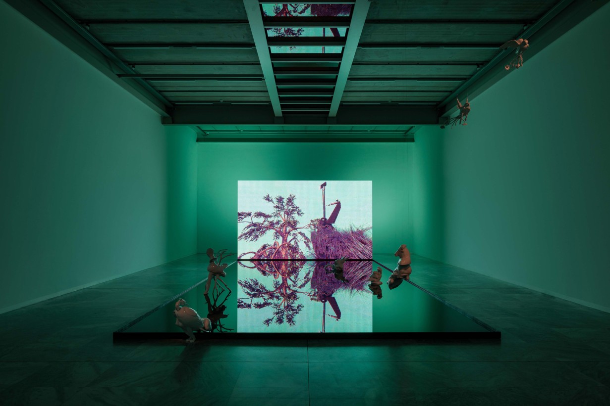 Exhibition space with a large screen at the back and a water area in front of it