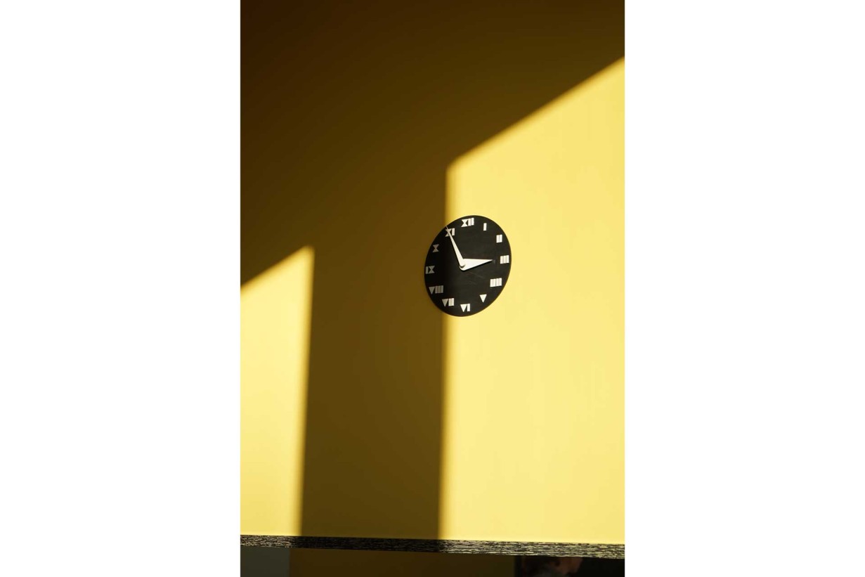 Eine Wanduhr an einer gelben Wand, die die Zeit anzeigt