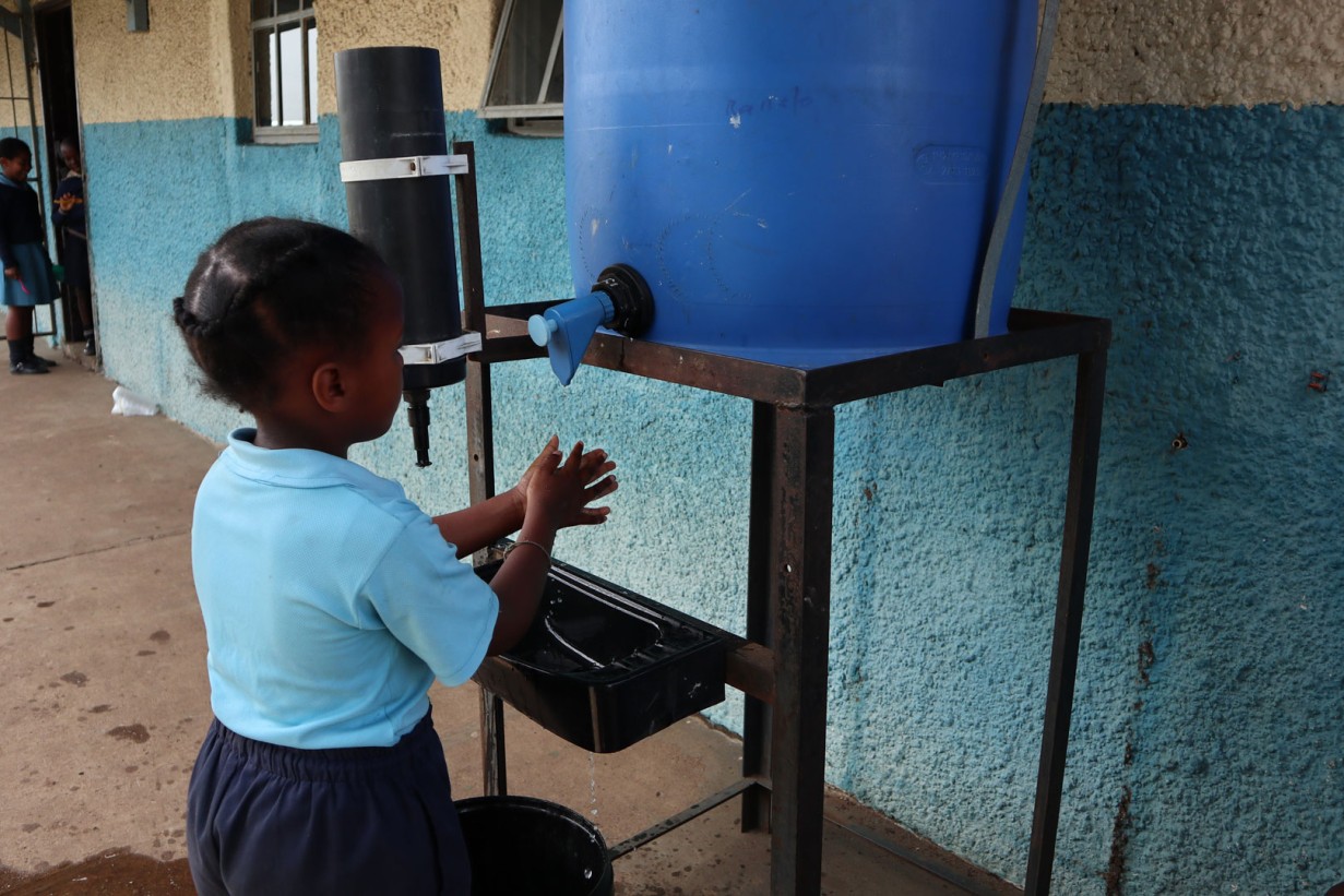Ein kleines Mädchen wäscht sich die Hände mit Wasser aus einem Kanister
