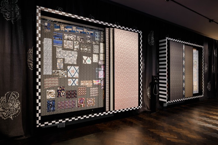 Stoffmuster der Wiener Werkstätte in einem schwarz-weiß gestreiften Rahmen