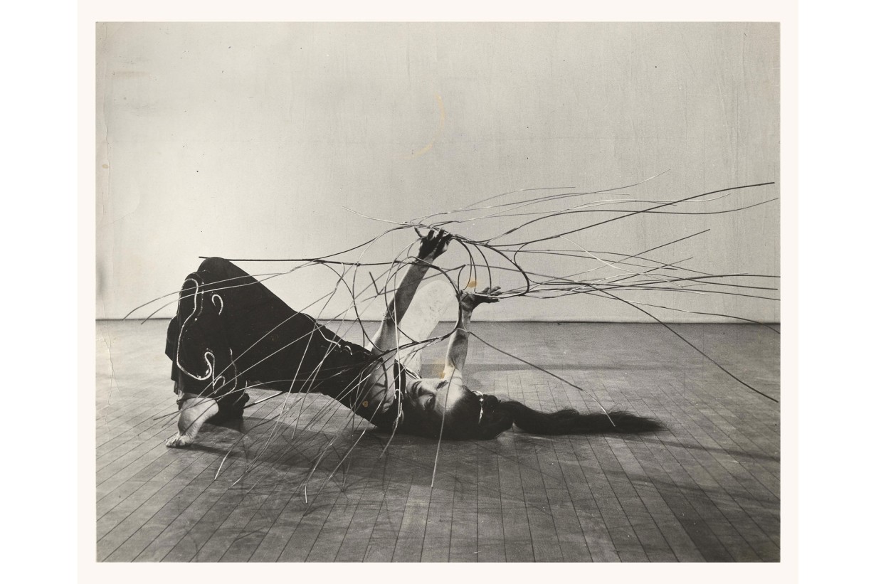 A dancer is lying half on the floor; her nails look as if they're growing into infinity