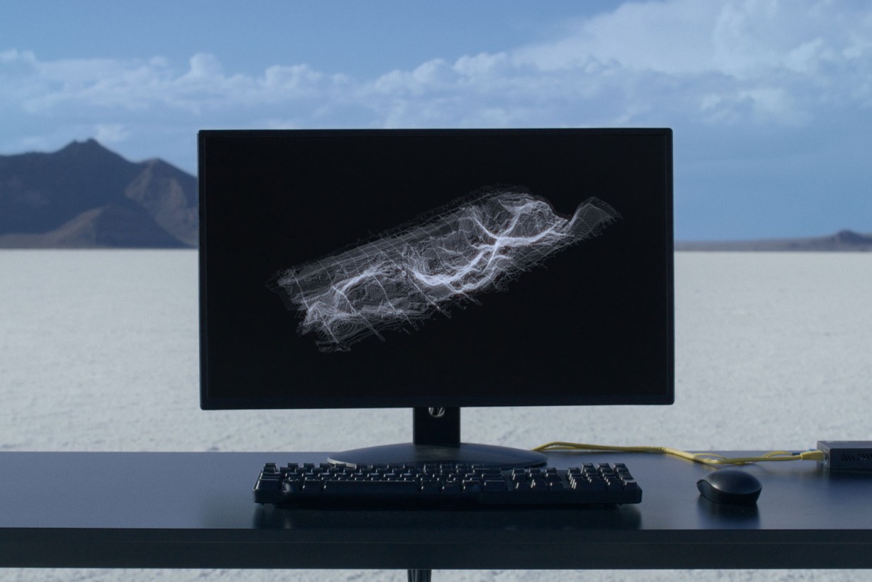 A computer screen on a desk stands in a desert landscape. 