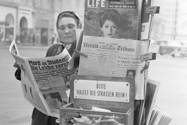 Schwarz weiß Fotografie von Frau an Zeitungsständer
