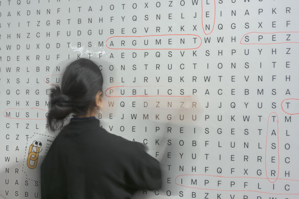 Weiße Wand mit Buchstaben, eine Person steht davor