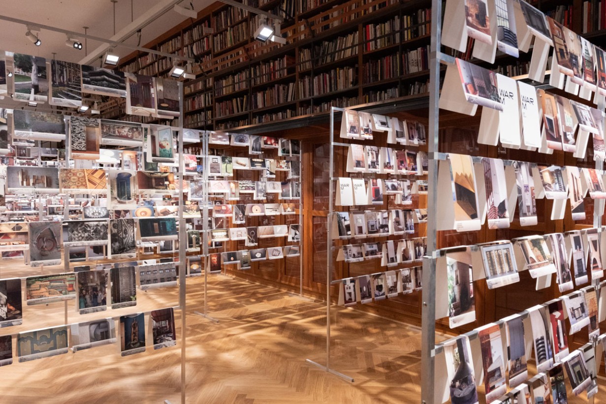 Viele Fotos mit Detailaufnahmen von Architektur hängen an an einem Gerüst in einem Ausstellungsraum.