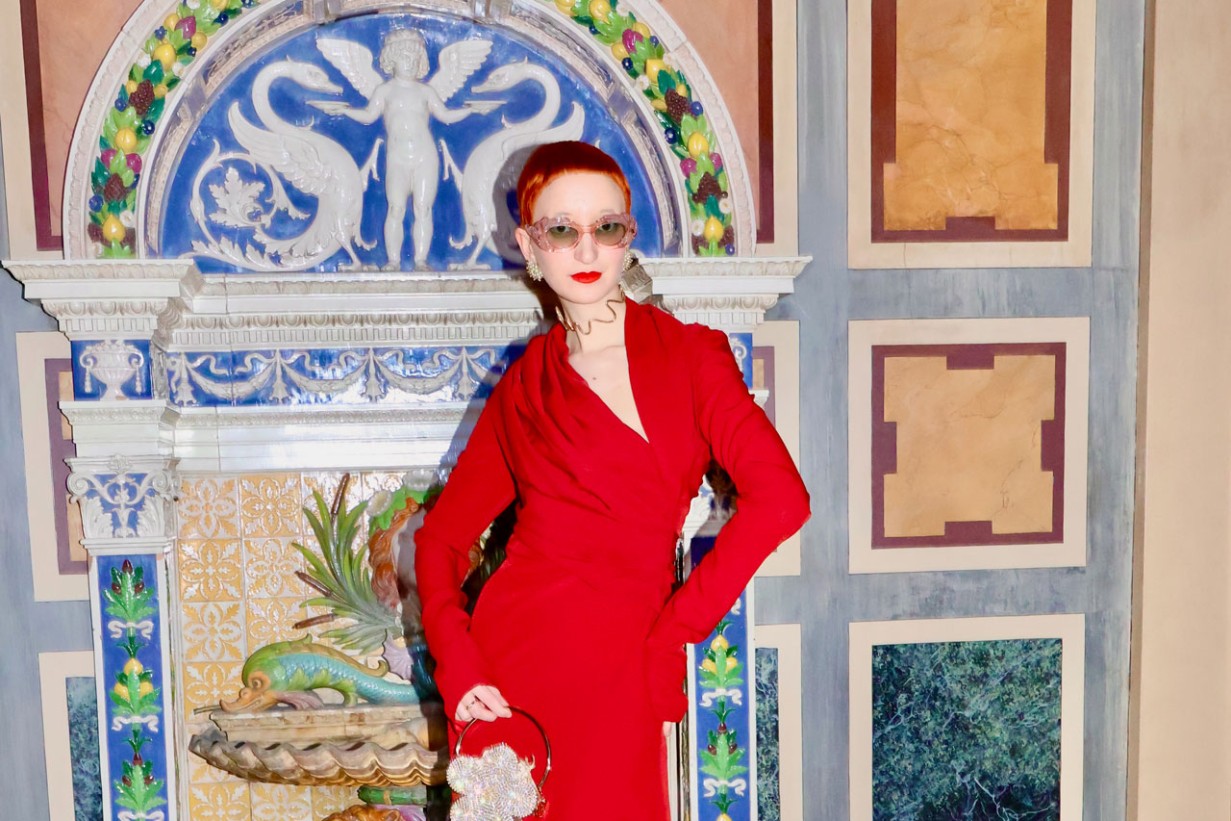 Eine Frau in rotem Kleid vor einem bunten Brunnen