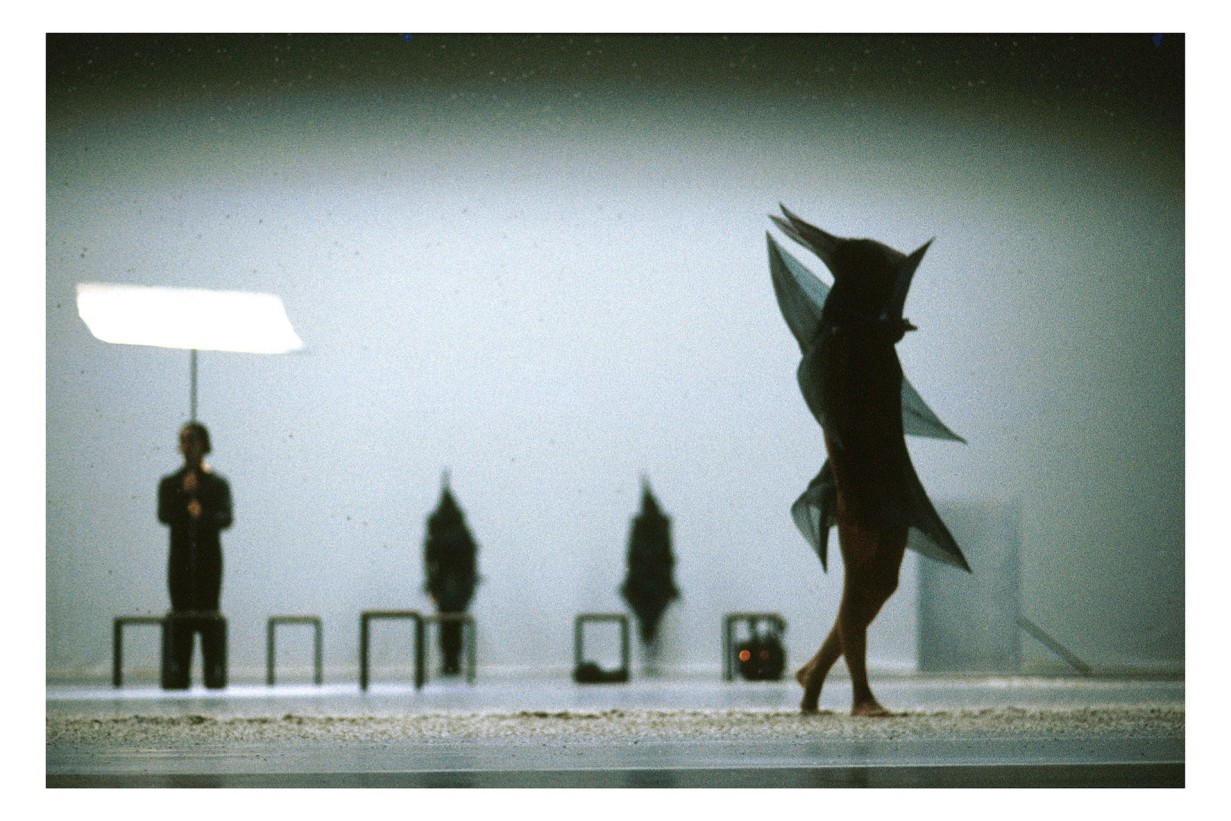Photograph of a dance scene; only the silhouettes of the dancers are visible