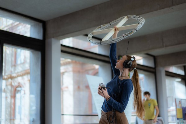 Person mit Kopfhörern hält selbstgebaute Antenne
