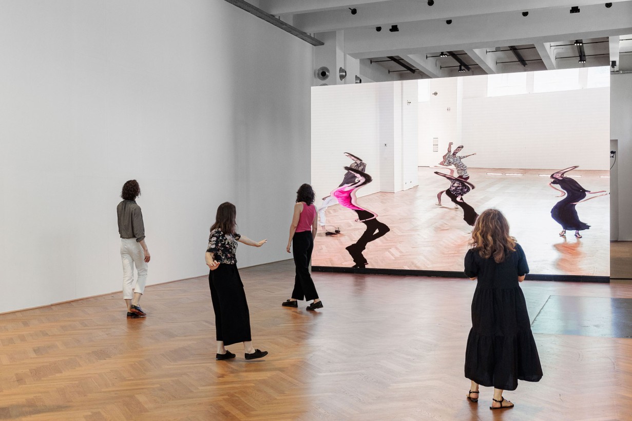 Eine Videowall vor der sich 5 Personen bewegen: Die Videowall verzerrt ihre Bewegungen.