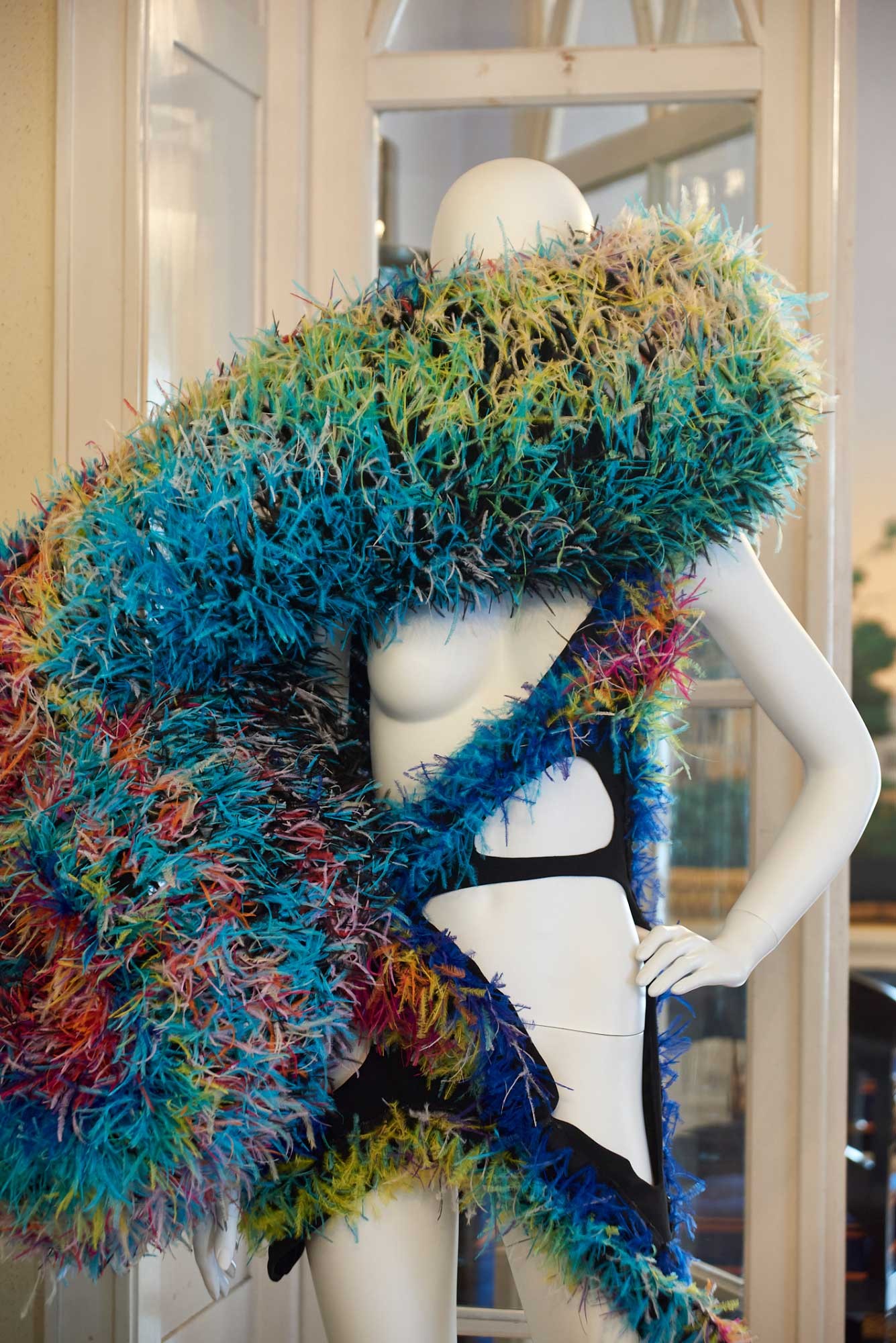 A mannequin around whose neck and body is wrapped a colorful object.