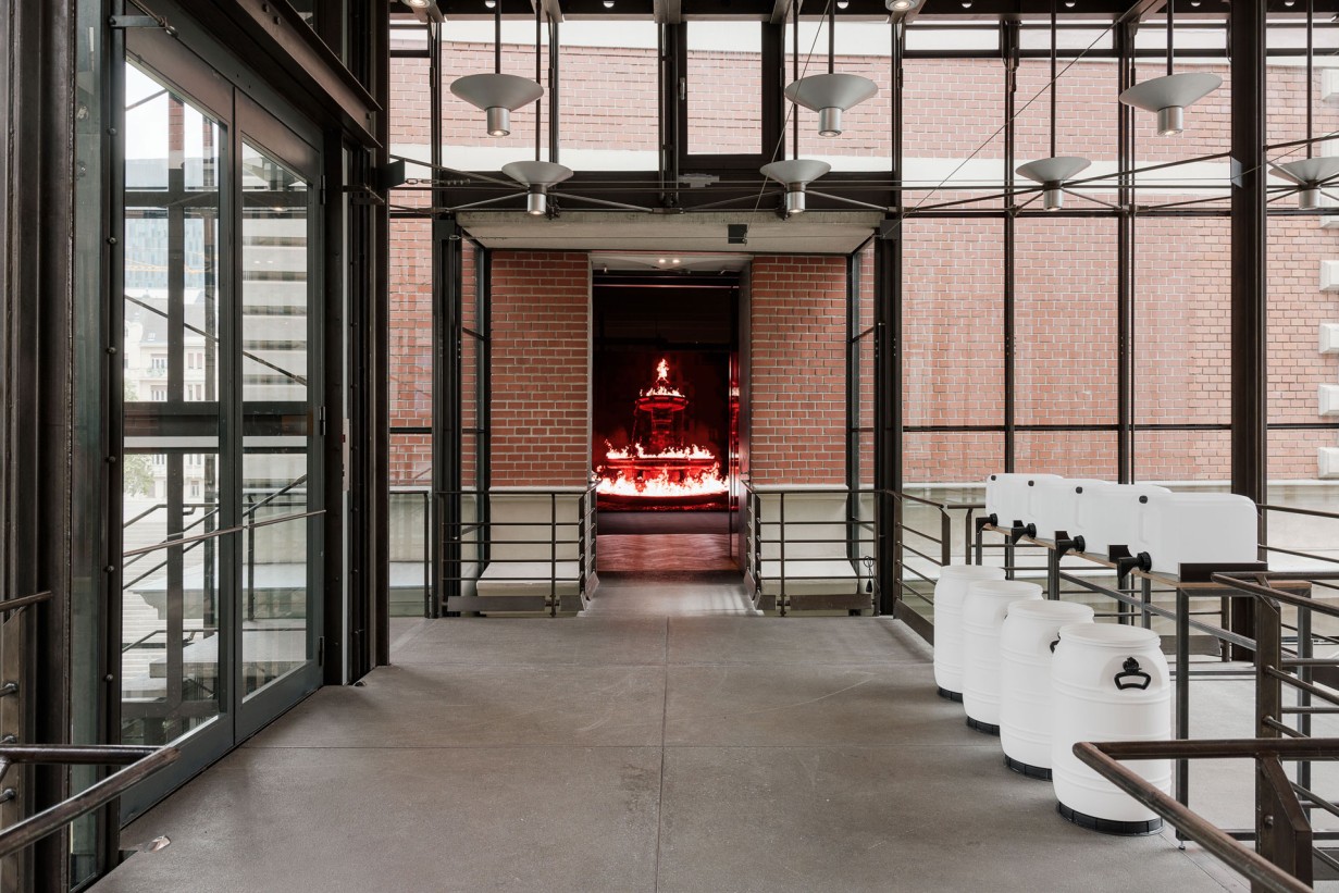 Blick in die Ausstellungshalle, im Hintergrund: Screen mit brennendem Brunnen