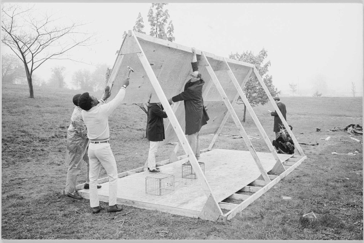 The architect John Wiebenson with a group of volunteers test-building one of the 650 A-frame houses. It was designed by the four-person structures committee and constructed by volunteers and camp residents during the first weeks of the protest.