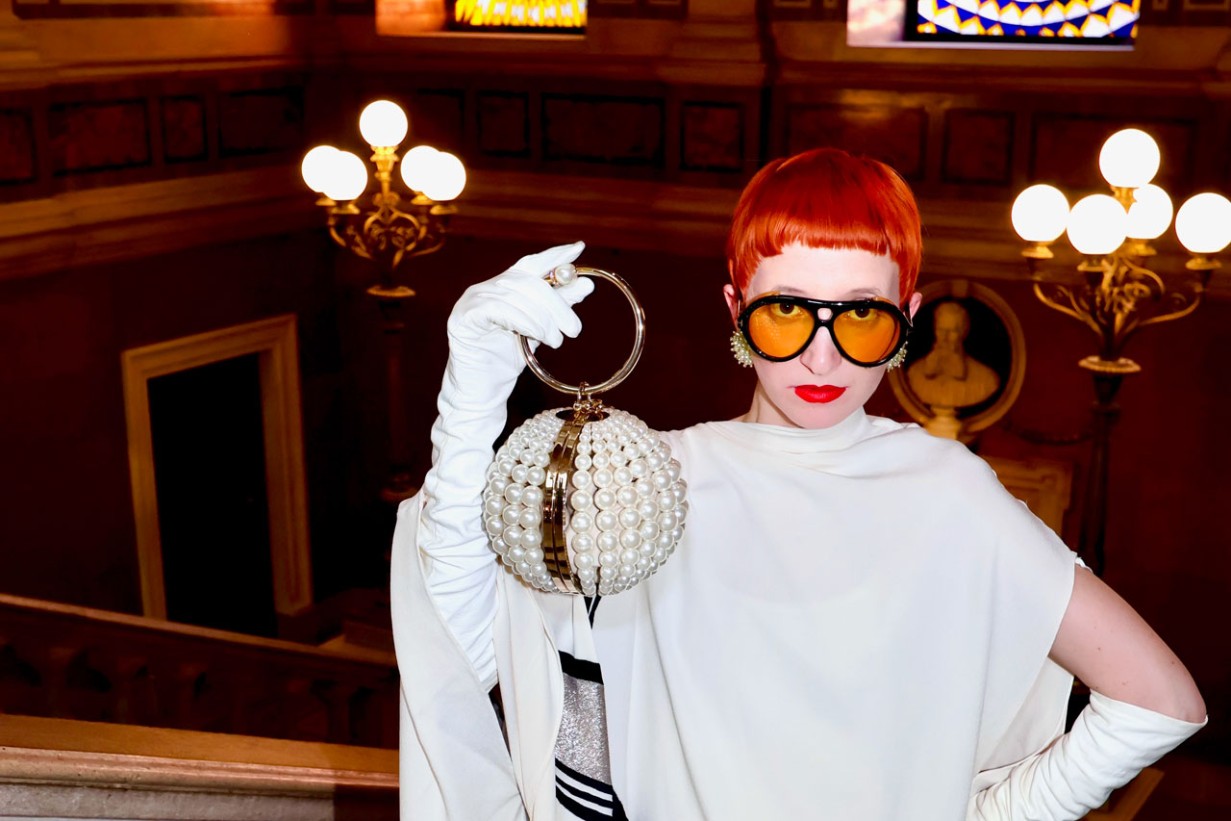 Eine Frau in weißem Kleid hält eine Kugel aus Perlen