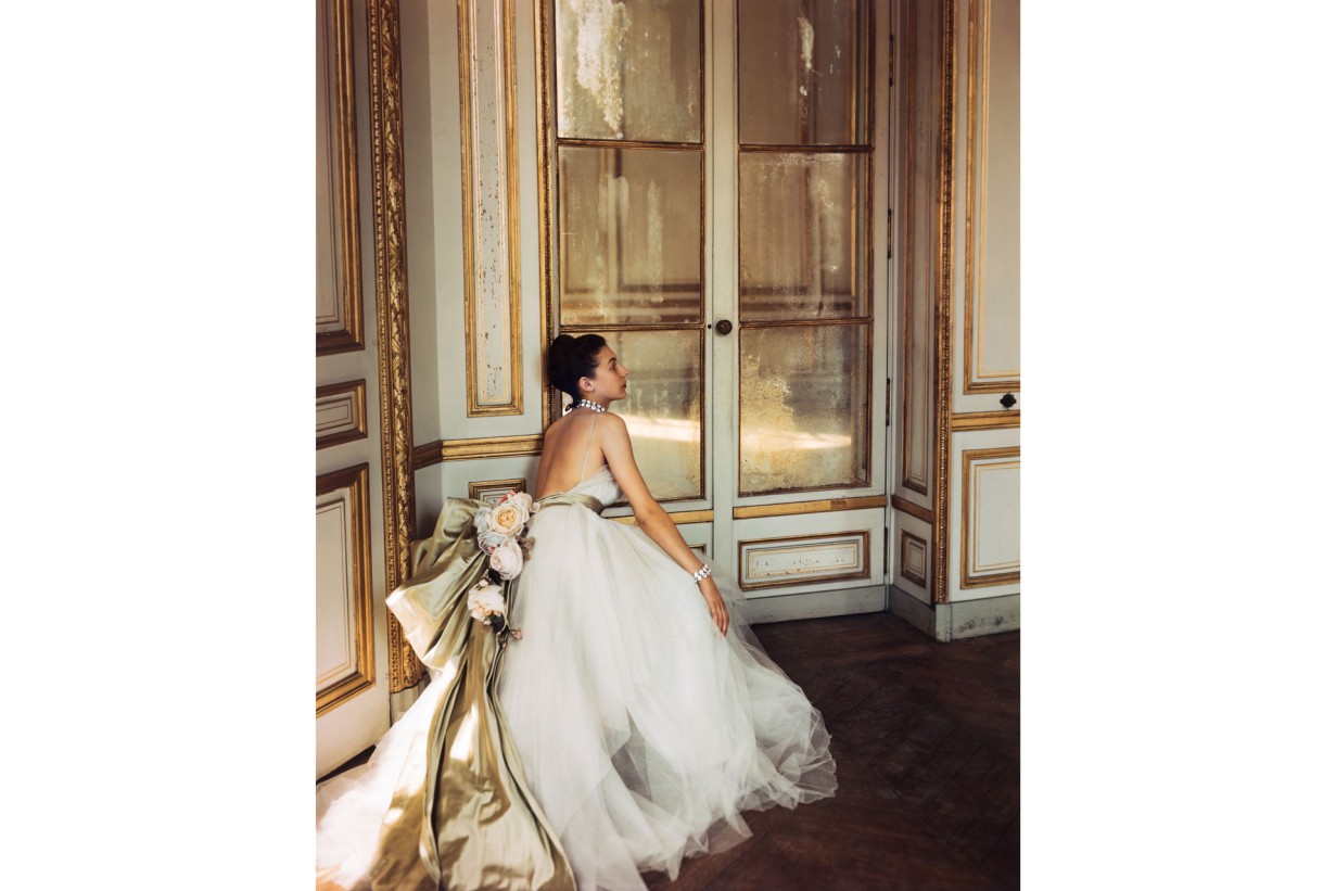 A woman in a Dior evening gown made of silk tulle and satin in a lavish room