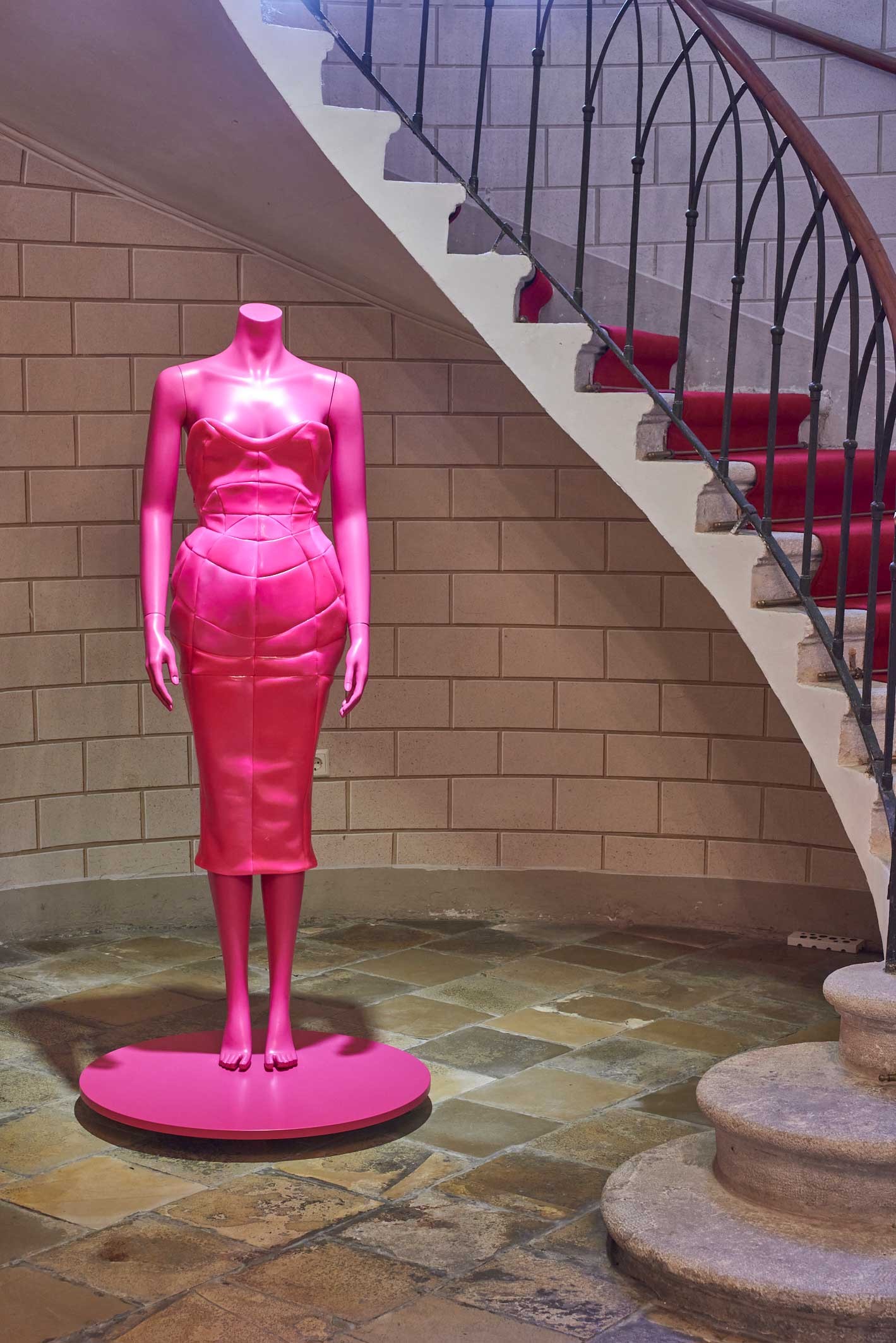A Biedermeier style room with a mannequin wearing a pink fashion design. 