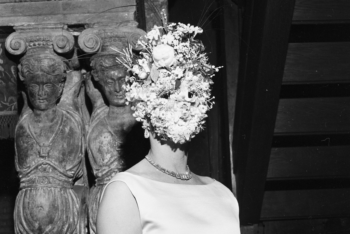 Person mit einer Maske aus Blumen vor dem Gesicht