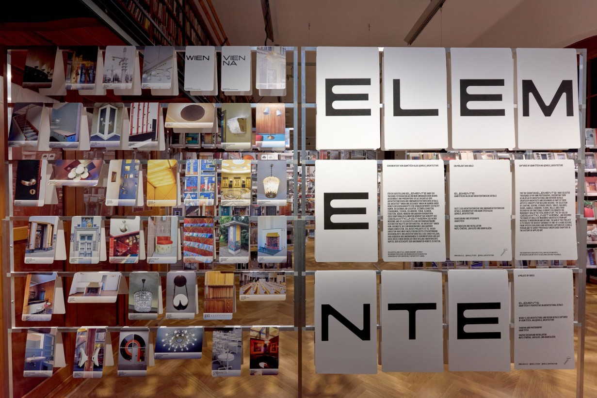 Viele Fotos mit Detailaufnahmen von Architektur hängen an an einem Gerüst in einem Ausstellungsraum. Daneben der Schriftzug "Elemente".