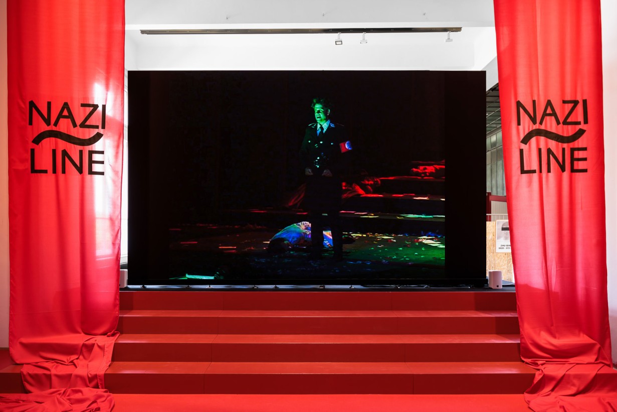 Treppe, Videowall, links und rechts davon Banner "Nazi Line" 