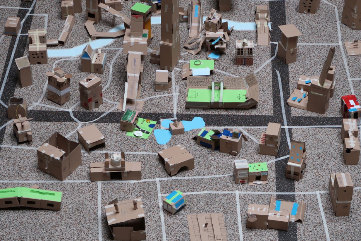 Modelle von Häusern, Wolkenkratzern und Straßen aus Pappe am Boden der MAK Säulenhalle. 
