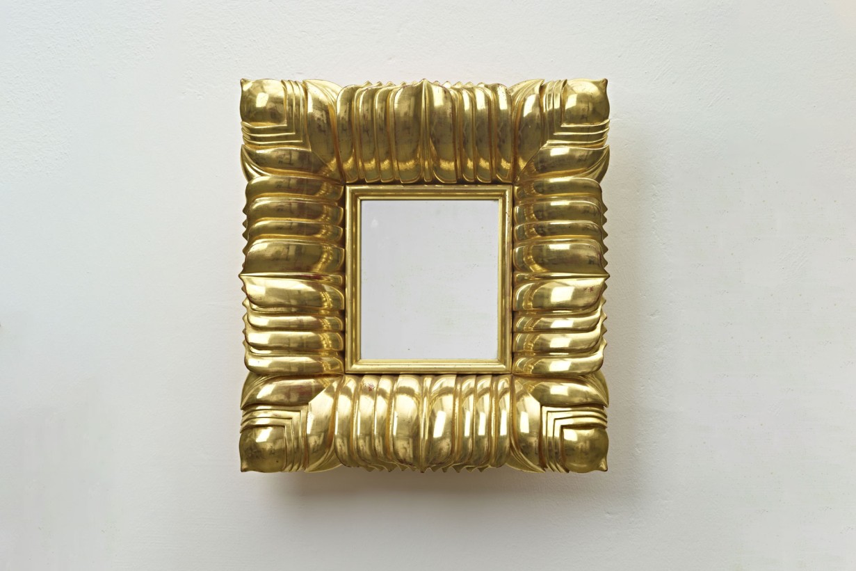 Ein goldener Spiegel mit quadratischem Rahmen