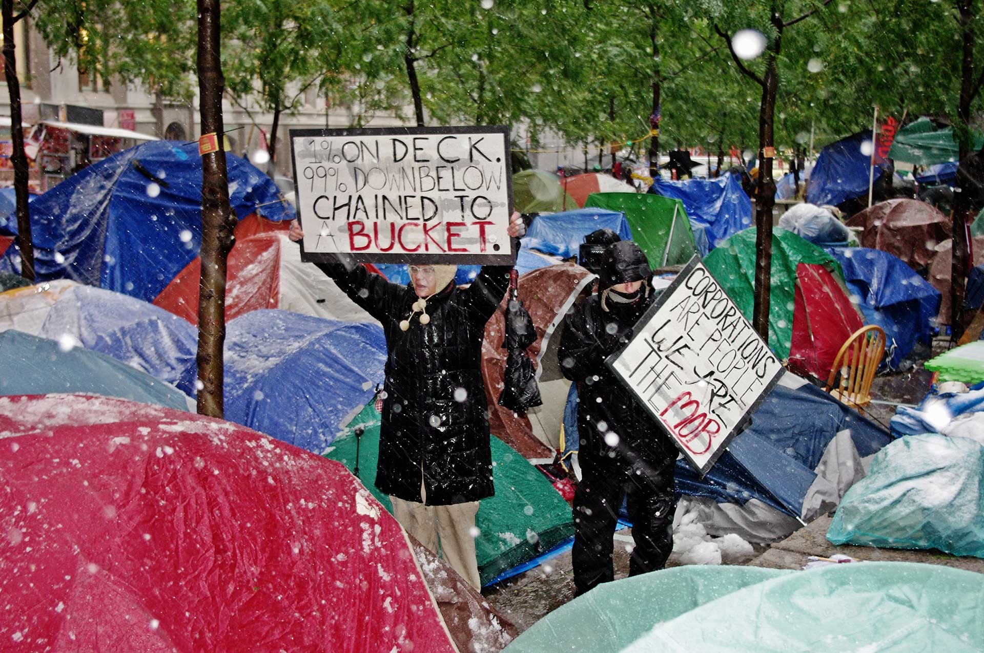 Protesters in snow-covered Zuccotti Park, a square in Manhattan’s financial district. The privately owned public space is controlled by  a company. The protest camp occupied the park for nine weeks and sparked a global protest movement with many other camps. A change in the weather transformed the camp from a radically open structure without any shelter from the elements into a dense city of private tents.