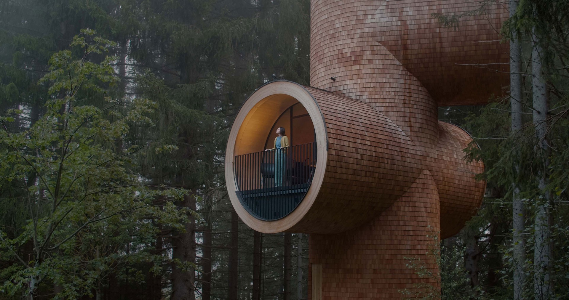 An oversized tree house in the shape of a tube in the middle of a forest.